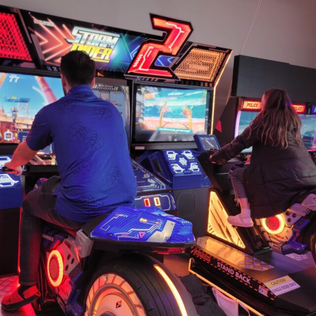 Enfants et adultes jouant à des jeux d’arcade interactifs au Centre Playbox, centre de divertissement familial à Montreal.