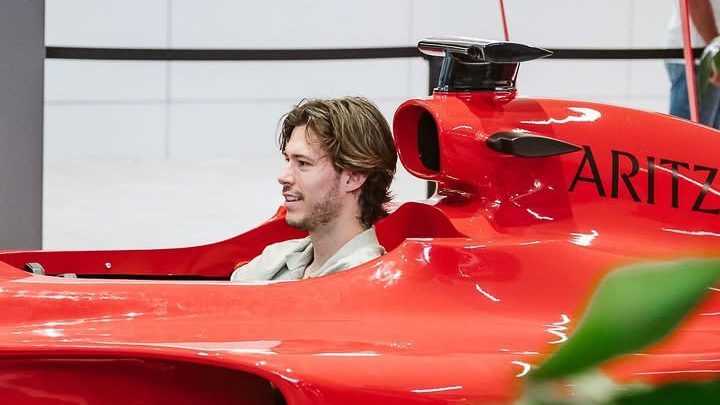 Homme assis dans une voiture de F1 rouge au Centre Eaton.