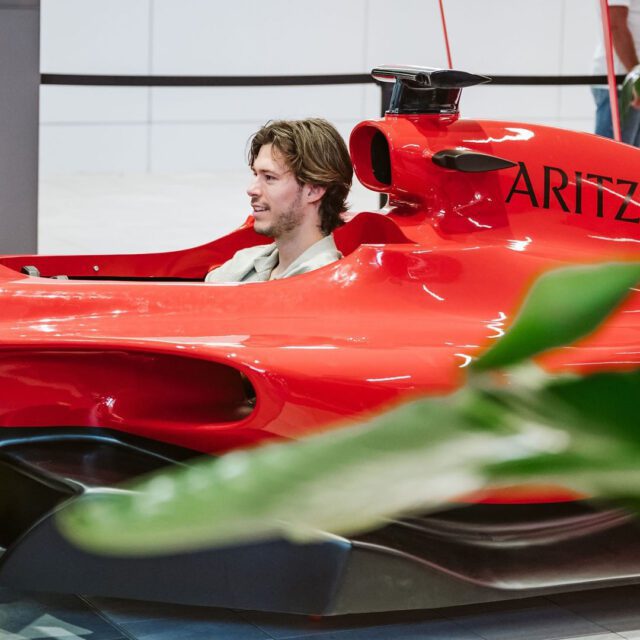 Homme assis dans une voiture de F1 rouge au Centre Eaton.