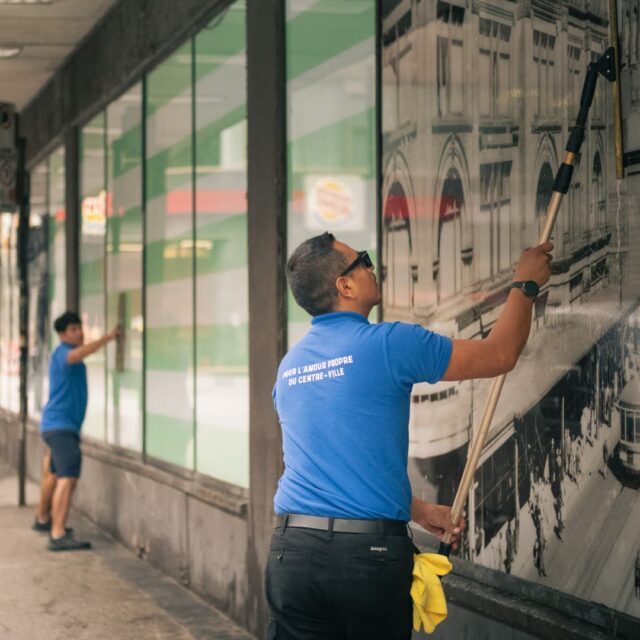 Les nettoyeurs des vitrines de la Baie d'Hudson au centre-ville de Montréal en pleine action