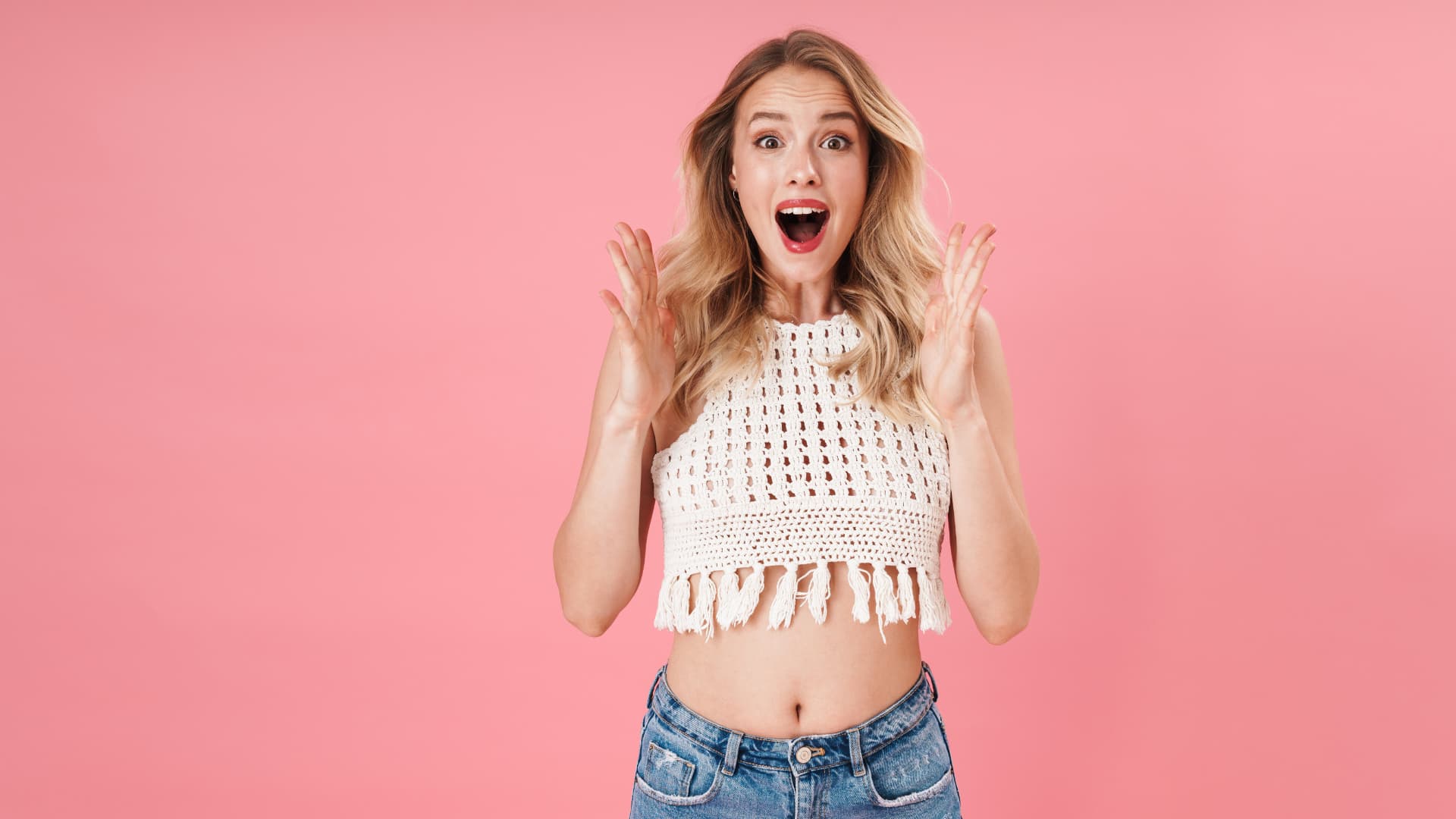 Jeune fille surprise devant un fond rose.