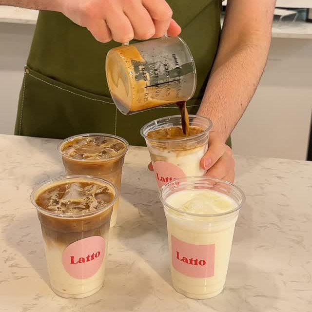 Un employé du café Latto versant du café dans des verres glacés, préparant des boissons lactées et glacées.