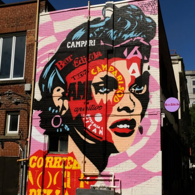 Une murale représentant le visage d'une femme sur le côté d'un restaurant.