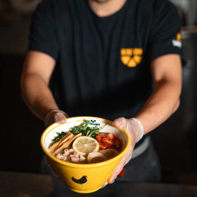 Un homme tient un bol de ramen.