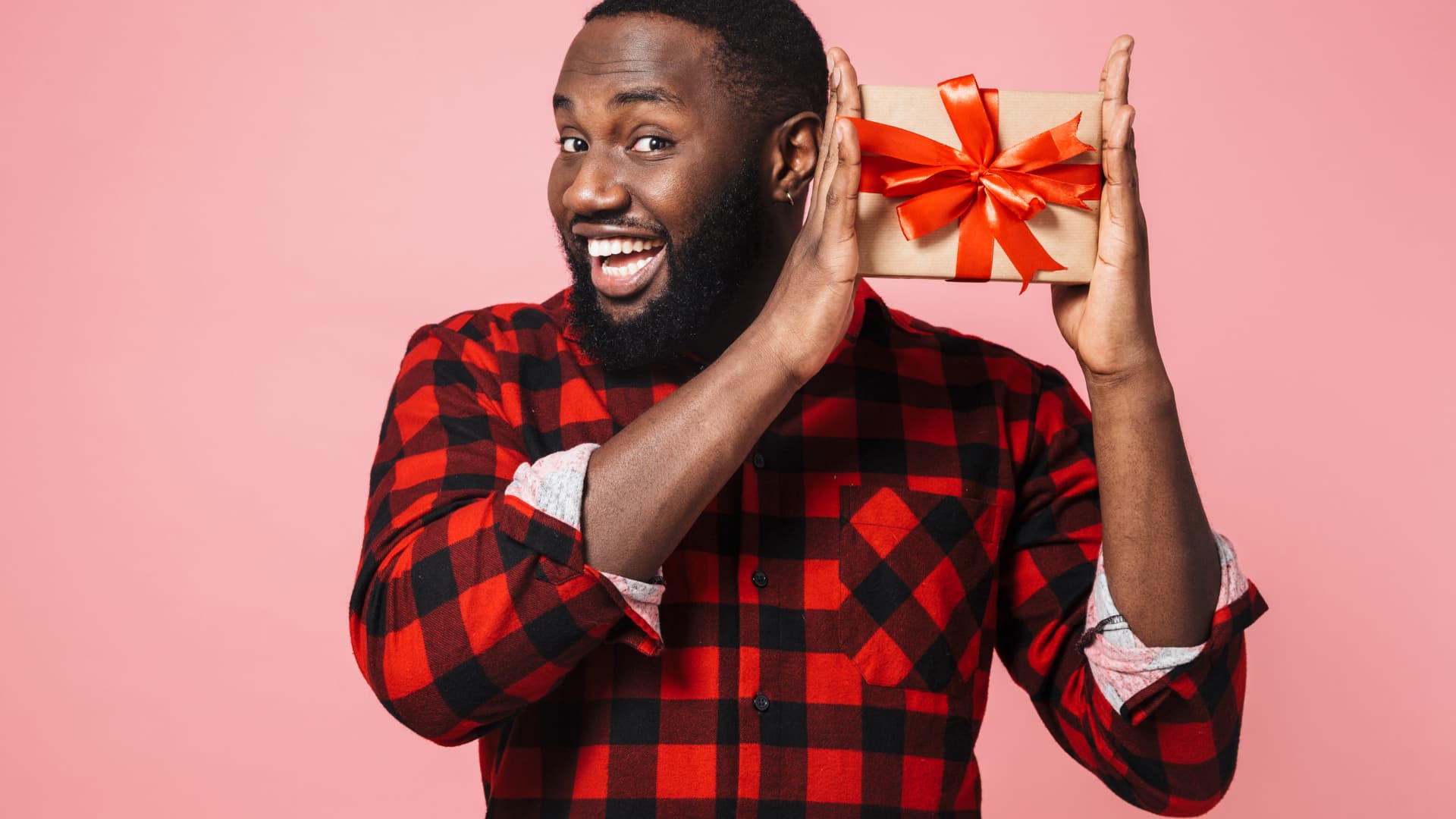 Homme en chemise à carreaux tenant un cadeau.