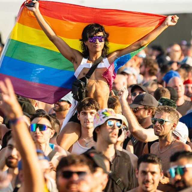 Foule au Festival Fierté Montréal avec drapeau arc-en-ciel au centre-ville.