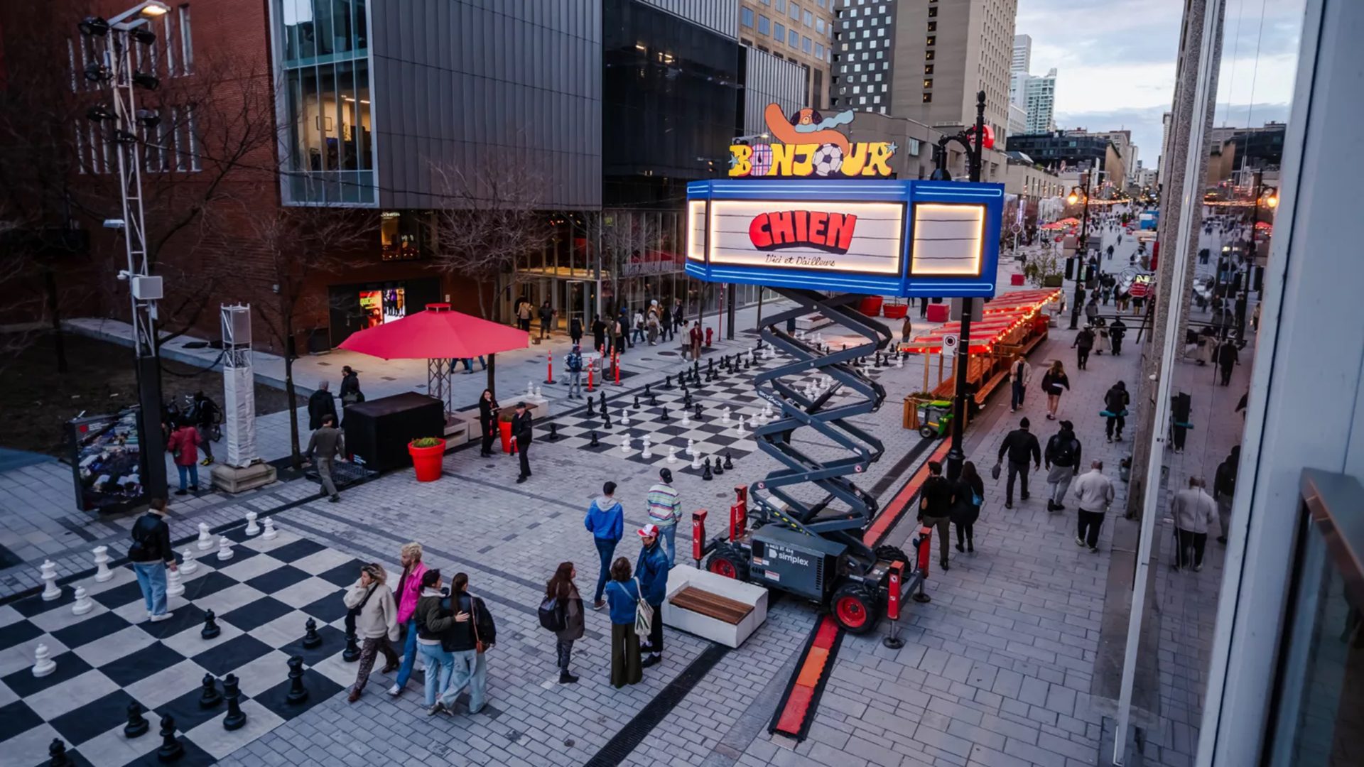 Installation artistique Bonjour Chien dans une rue du centre-ville de Montréal avec œuvres colorées et passants.