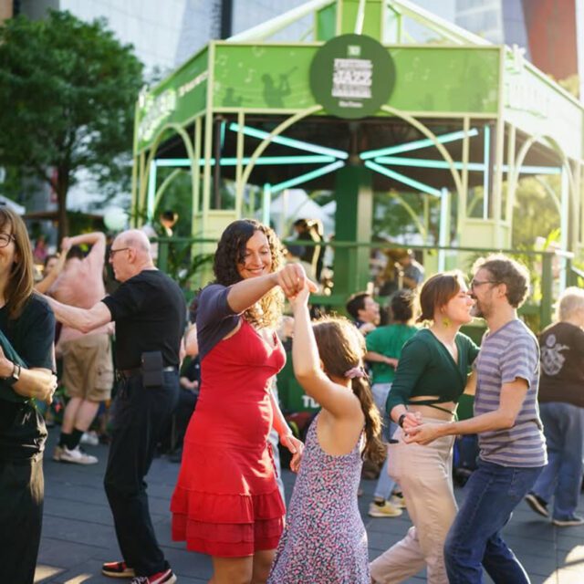 Festival de Jazz de Montréal en soirée au Quartier des spectacles avec foule et danse devant la scène.