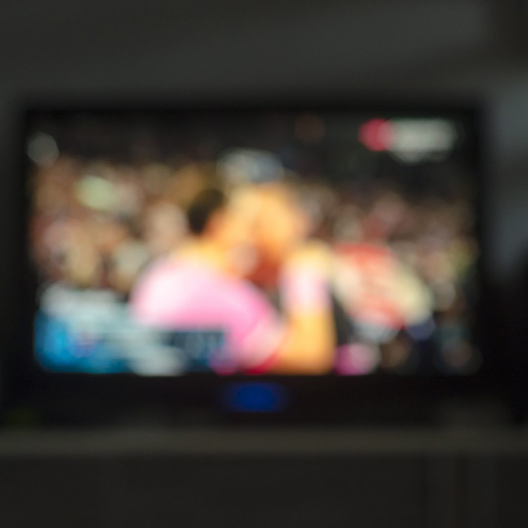 Écran diffusant un match de soccer vu en arrière-plan flou