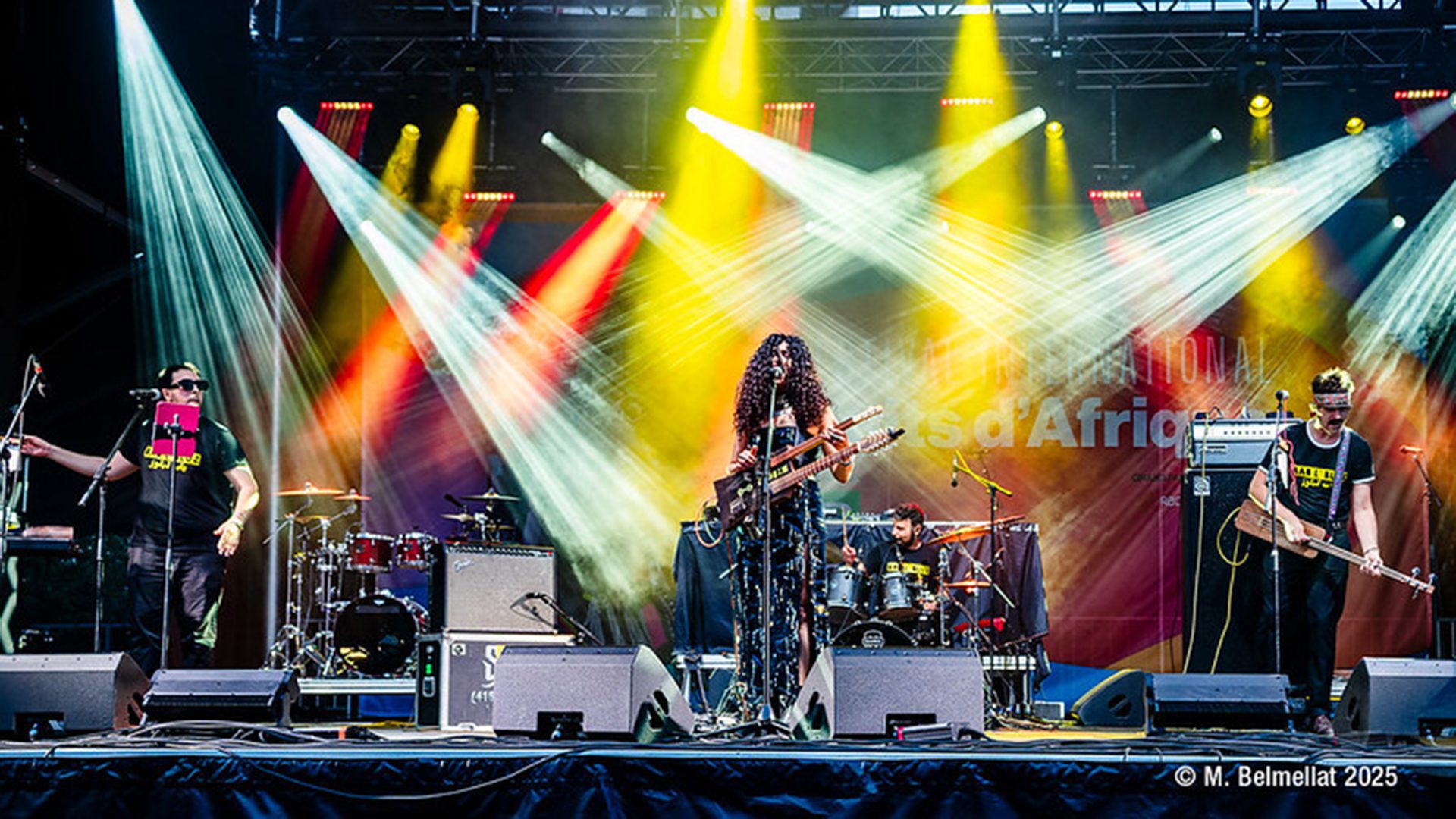 Artistes sur scène sous des jeux de lumière colorés lors du Festival international Nuits d’Afrique à Montréal.